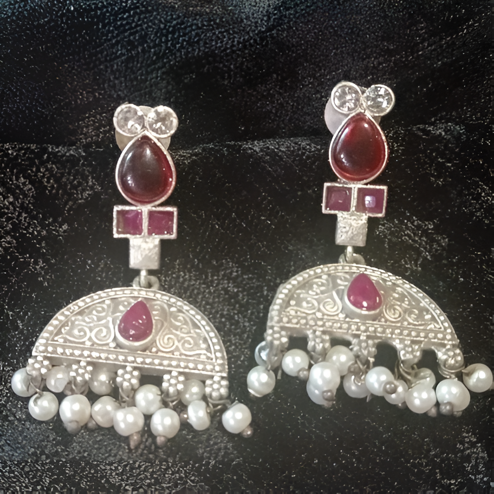 Pair of silver oxidised ethnic earrings with red gemstones and pearl drops .