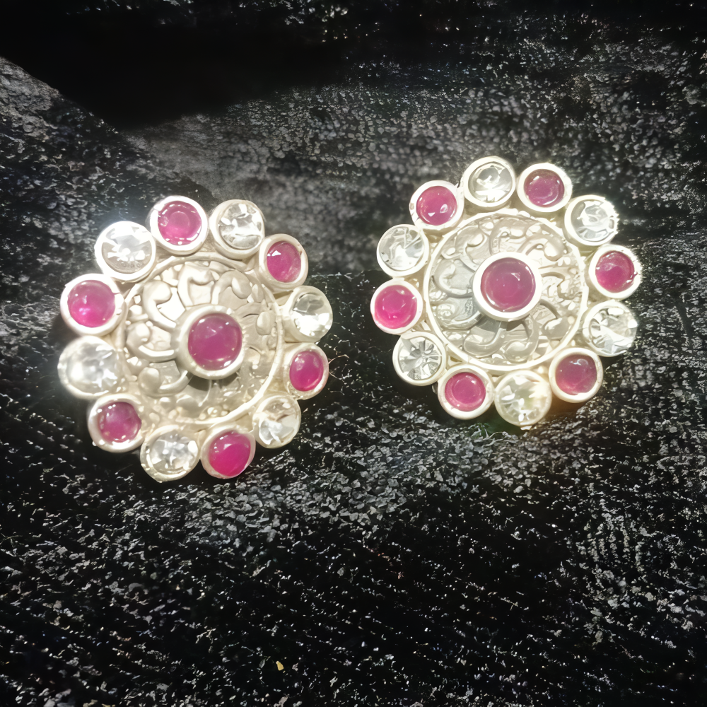 Pair of silver oxidised earrings with pink & clear kundan stones on a black textured background