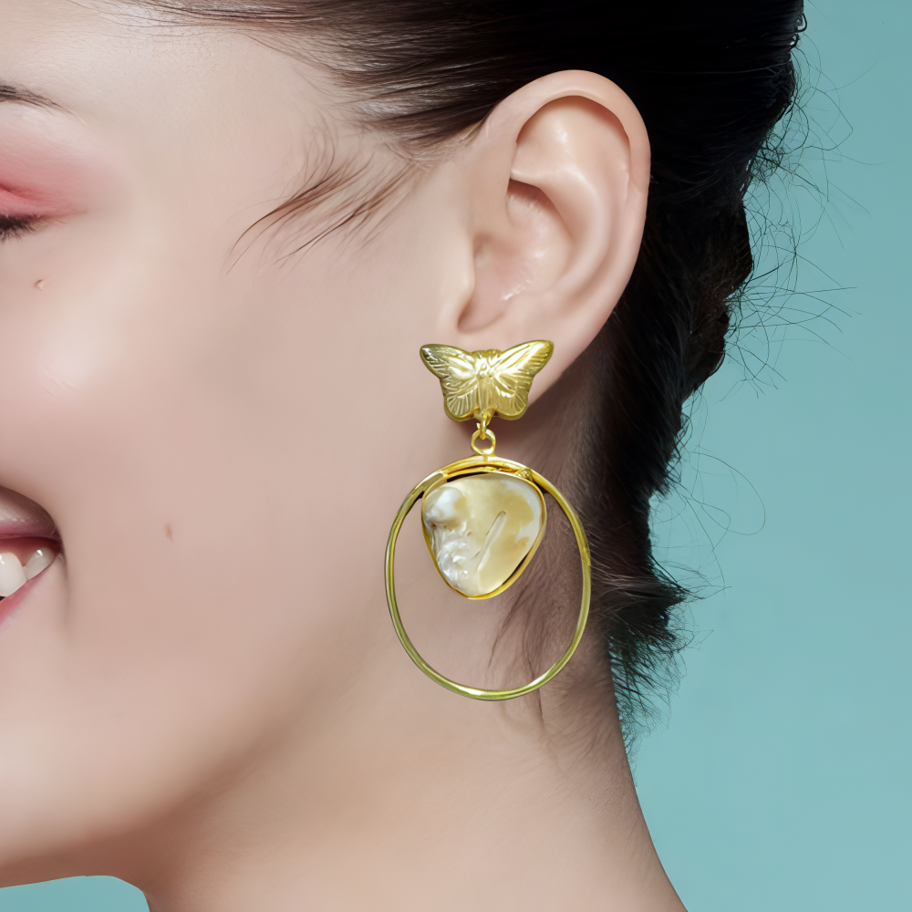 Gold butterfly earrings with a circular design & stone within worn by a model