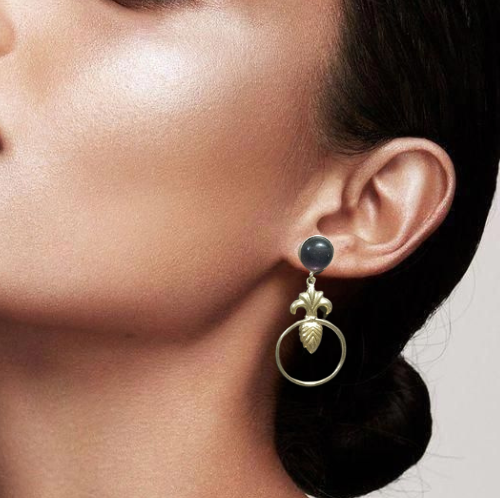 Close up of a model wearing golden dangle earrings with black stone