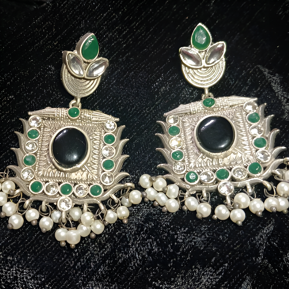 Ornate earrings with black centers, green accents, and pearl-like beads .