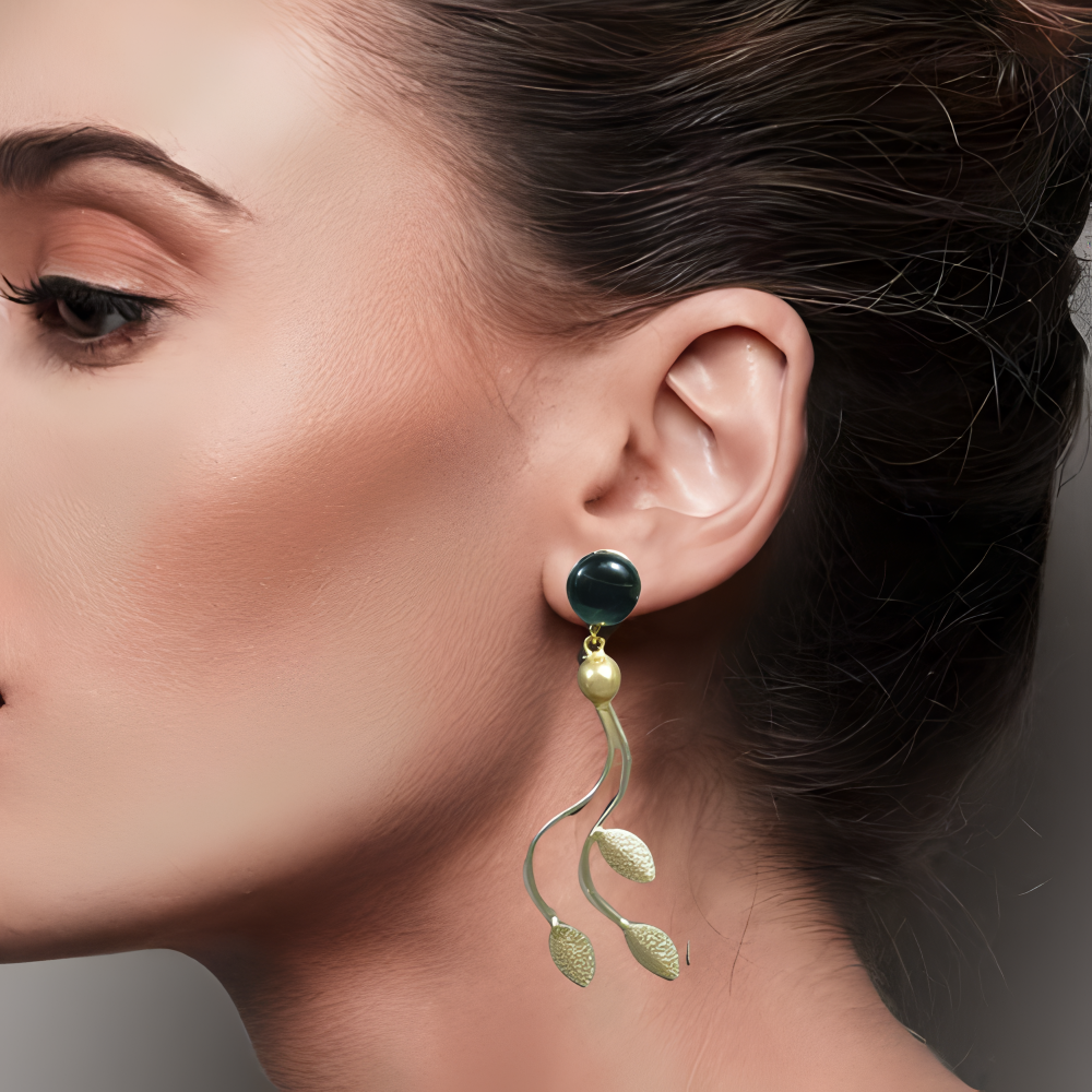 Close-up of a woman wearing a stylish westren gold earring with transparent green stone .
