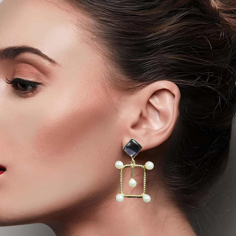 Picture of a model wearing a gold earring with a central dark stone and smaller pearls.