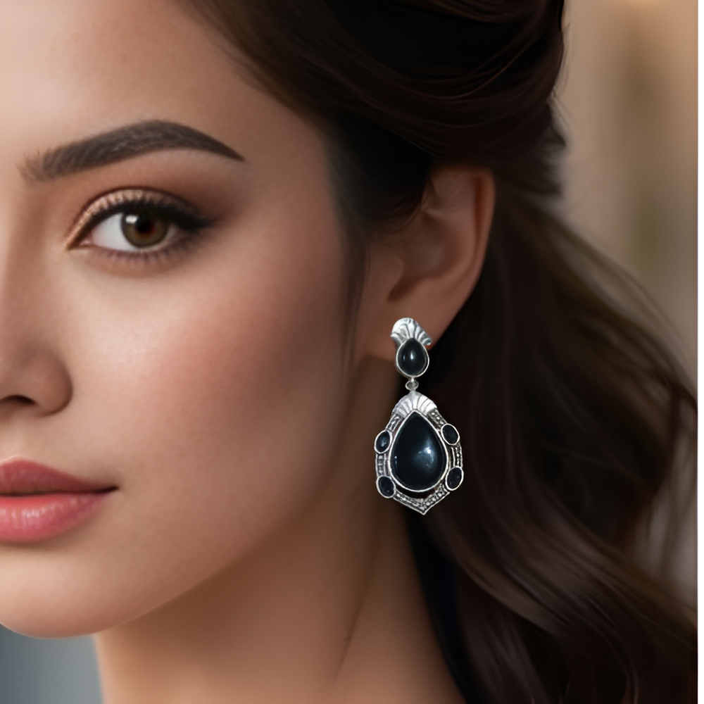 Close-up of a woman wearing elegant silver oxidised black teardrop earrings .