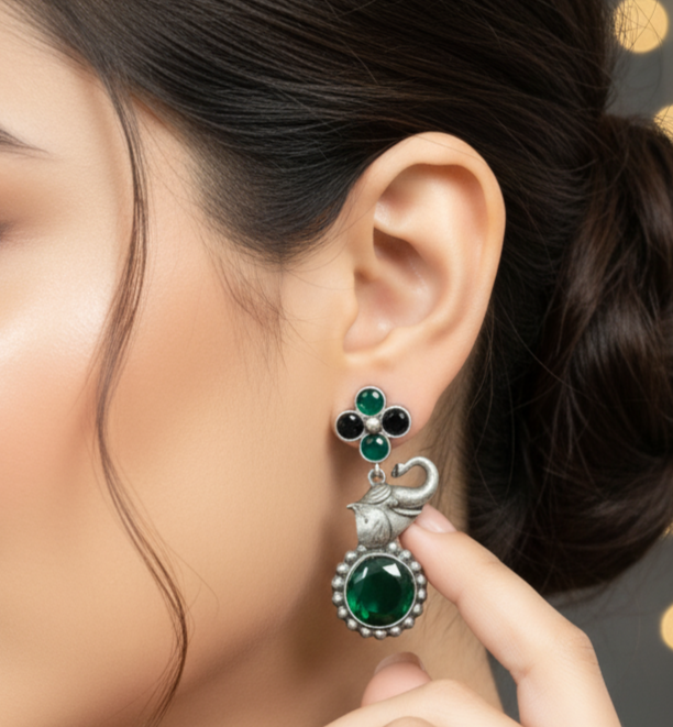 Pair of elephant earrings for women with green gemstones and silver accents on a white background