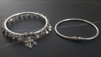 Two silver ankle bracelets on a dark surface