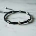 Black macrame ankle bracelet with silver beads on a marble surface
