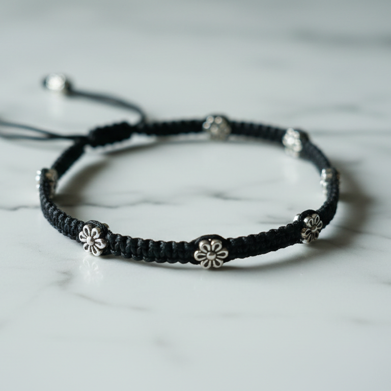 Black macrame ankle bracelet with silver beads on a marble surface