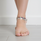 Foot wearing a colorful anklet on a light background