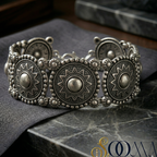 Decorative silver ankle bracelet on a dark fabric surface with a blurred background
