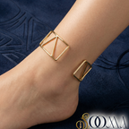 Closure Side of Gold anklet on a person's ankle against a dark blue textured background
