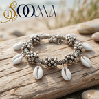 Silver bracelet with shell charms on a wooden log with a blurred natural background