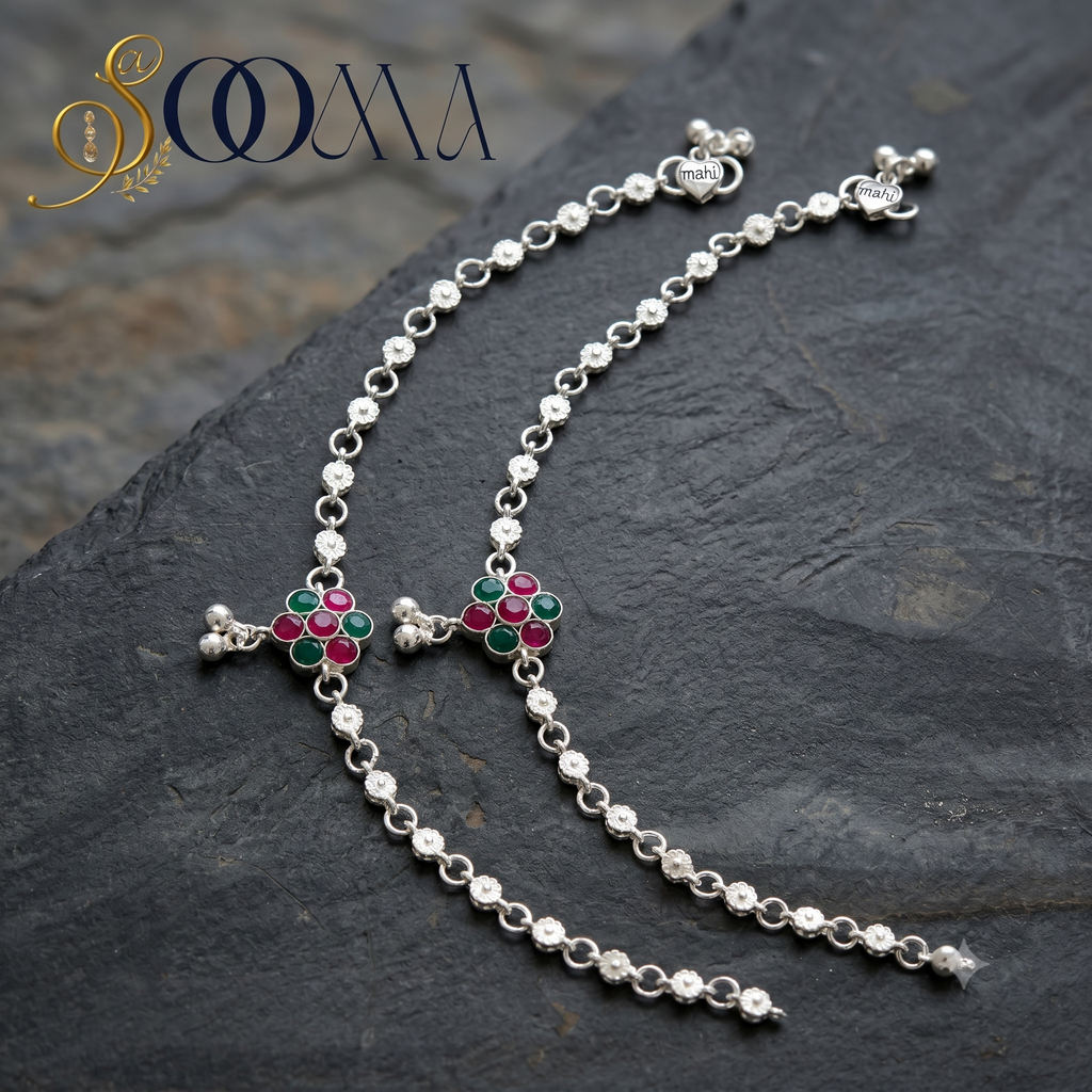 Silver bracelet with floral designs on a dark stone surface, featuring the brand 'Sooma'.