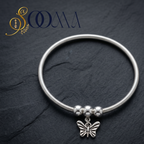 Polished silver ankle jewelry with an antique-finished butterfly charm close up