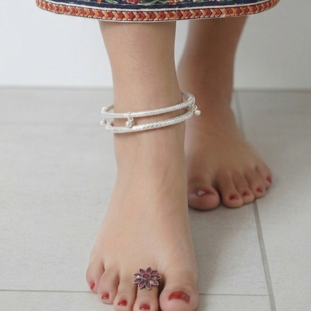 Close-up of feet wearing anklets with a colorful floral-patterned garment.