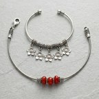 Silver anklett with red beads & charm anklet on a light gray background