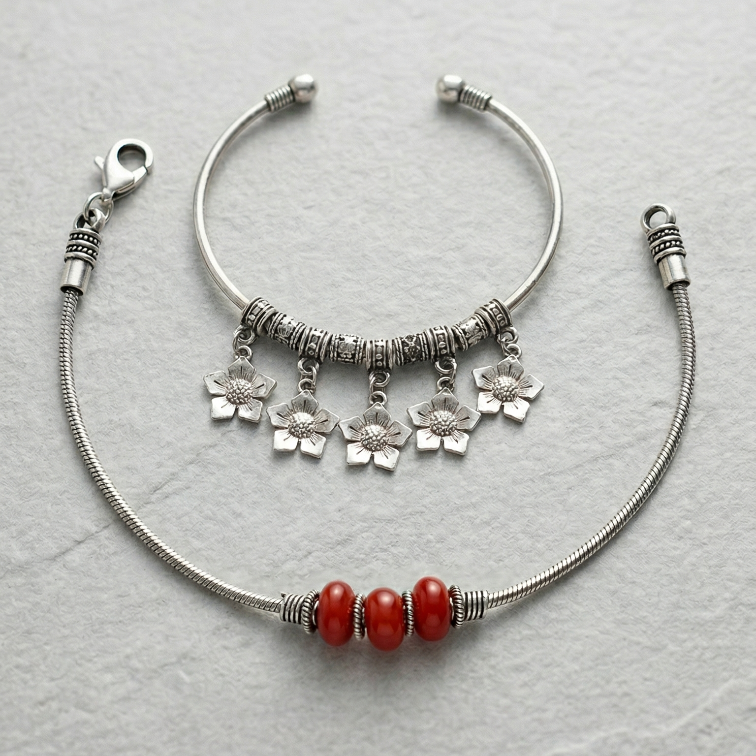 Silver anklett with red beads & charm anklet on a light gray background