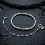 Oxidized silver payal anklet & kada with intricate design on a earthy surface
