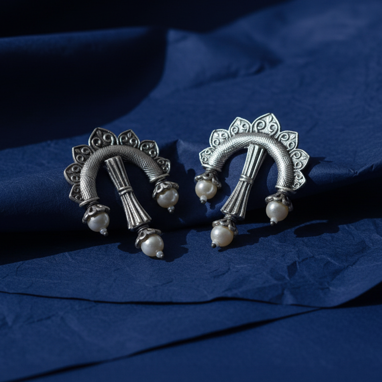 Statement oxidized stone earrings showcasing intricate stone setting and antique finish on a blue surface.