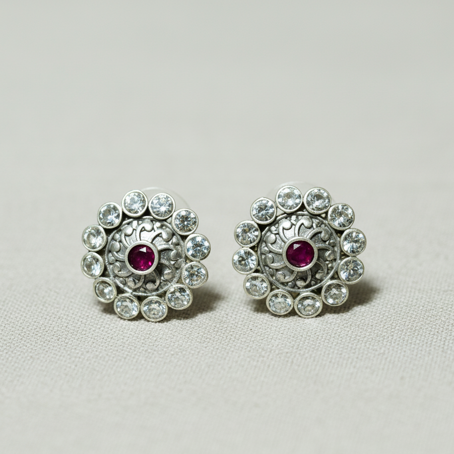 Pair of silver earrings with red gemstones on a light gray background