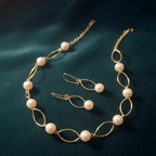 Gold necklace with pearls with dangle earrings on a dark blue fabric background