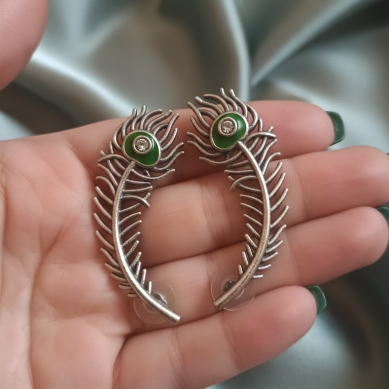 Close-up of a handcrafted peacock earcuff showcasing intricate details and shimmering stones.