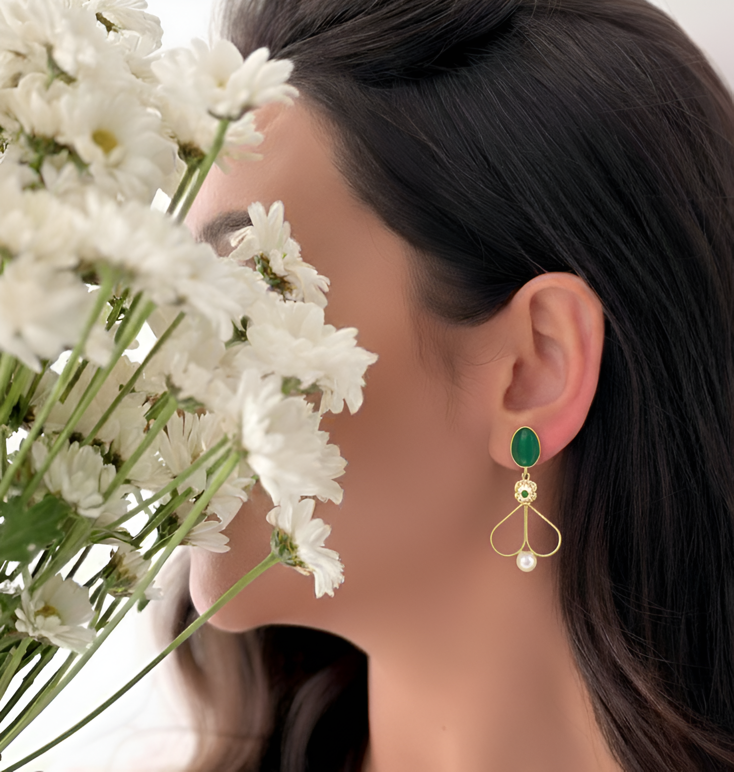 Close-up of a woman's ear with Elegant Evil Eye Green Dangle Earrings.