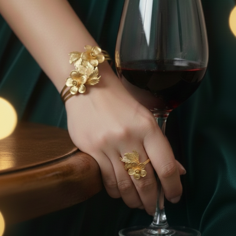 Hand holding a glass of red wine with Elegant Gold Floral Bracelet Ring Set .
