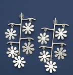 Long floral oxidized silver contemporary earrings on a blue background .