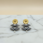 Close-up of Flower Dual Tone Earrings showcasing the floral design and dual-tone finish, on a marble surface .
