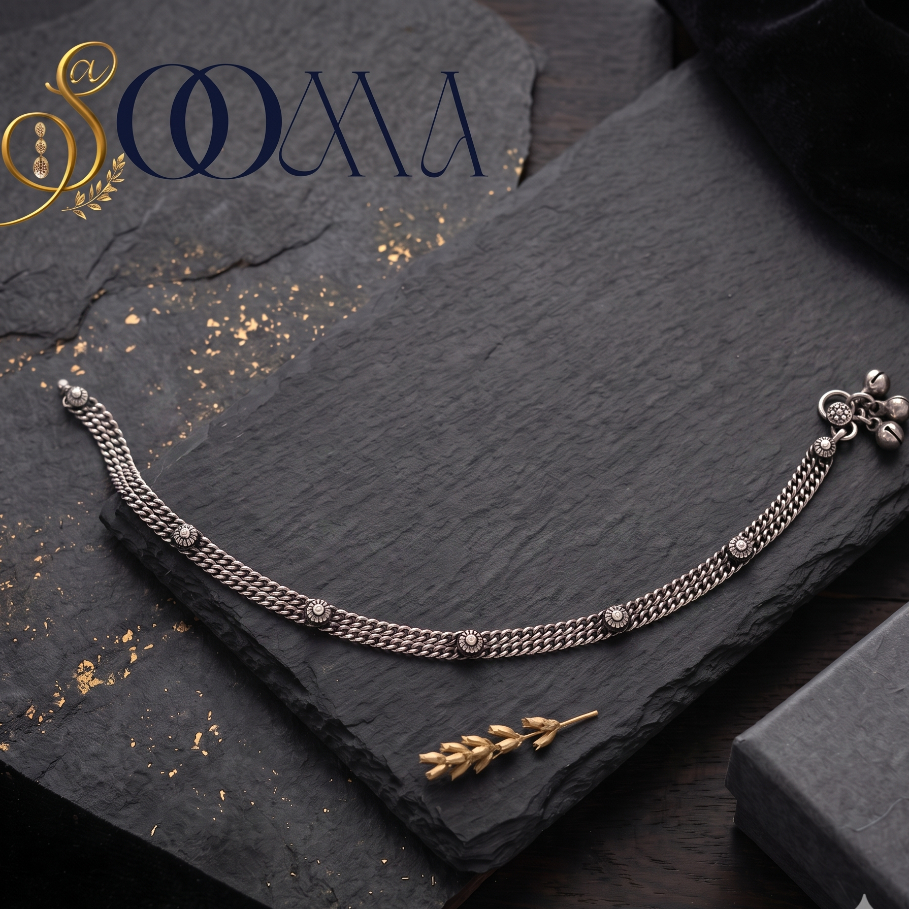 Sooma brand handcrafted oxidized silver double curb link anklet with rosette motifs displayed flat on a dark slate slate board with a black gift box