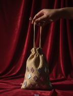 Hand holding a small drawstring bag with geometric mirror