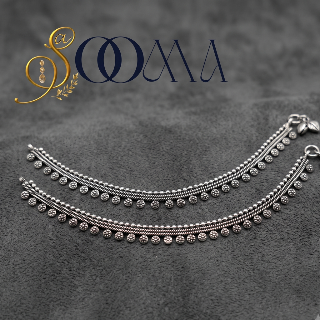 Sooma brand pair of oxidized silver floral drop payal anklets displayed flat on a textured grey surface