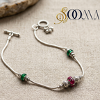 Silver ankle bracelet with colored beads on a textured beige surface, featuring the brand 'Sooma'.