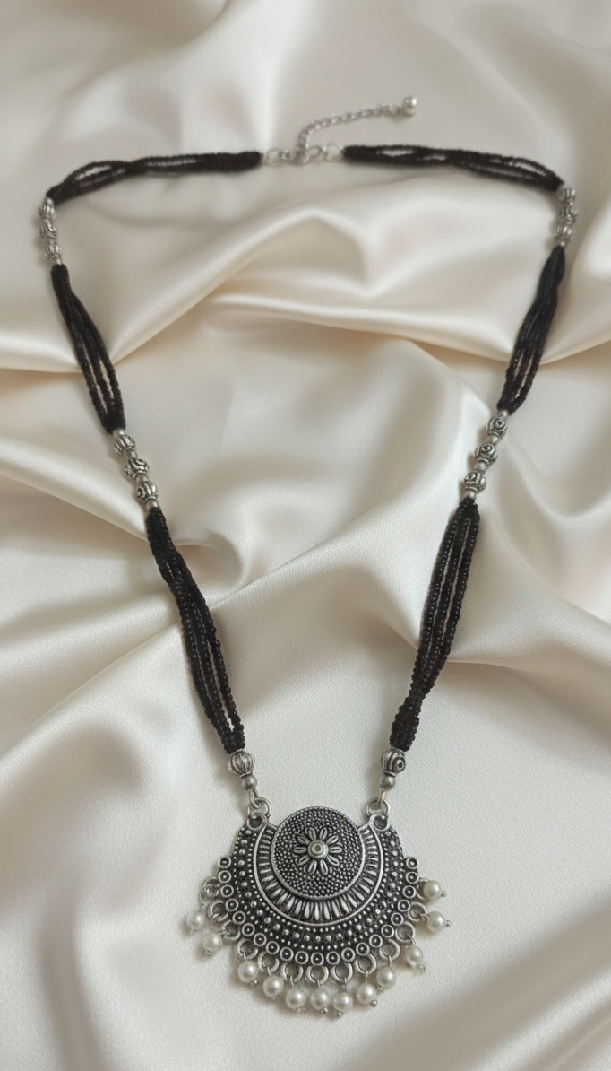 Close-up of a black bead necklace with an oxidised finish.