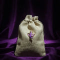 Drawstring bag with a purple ganesha charm on a dark purple background
