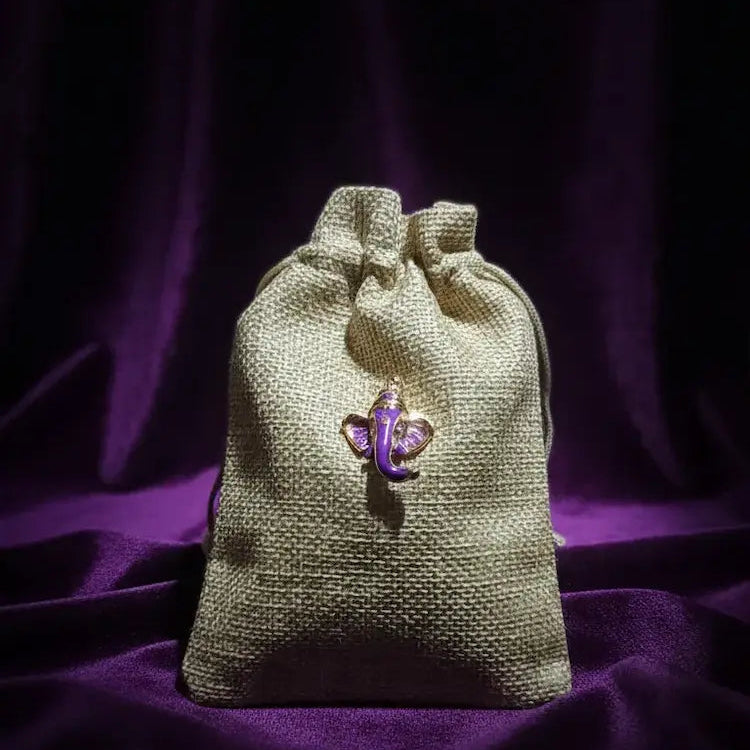 Drawstring bag with a purple ganesha charm on a dark purple background
