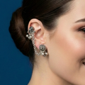 Woman wearing floral chain cuff earrings against a blue background
