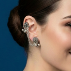 Woman wearing floral chain cuff earrings against a blue background