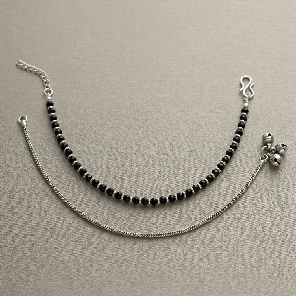Anklets with black beads and silver chain on a beige background