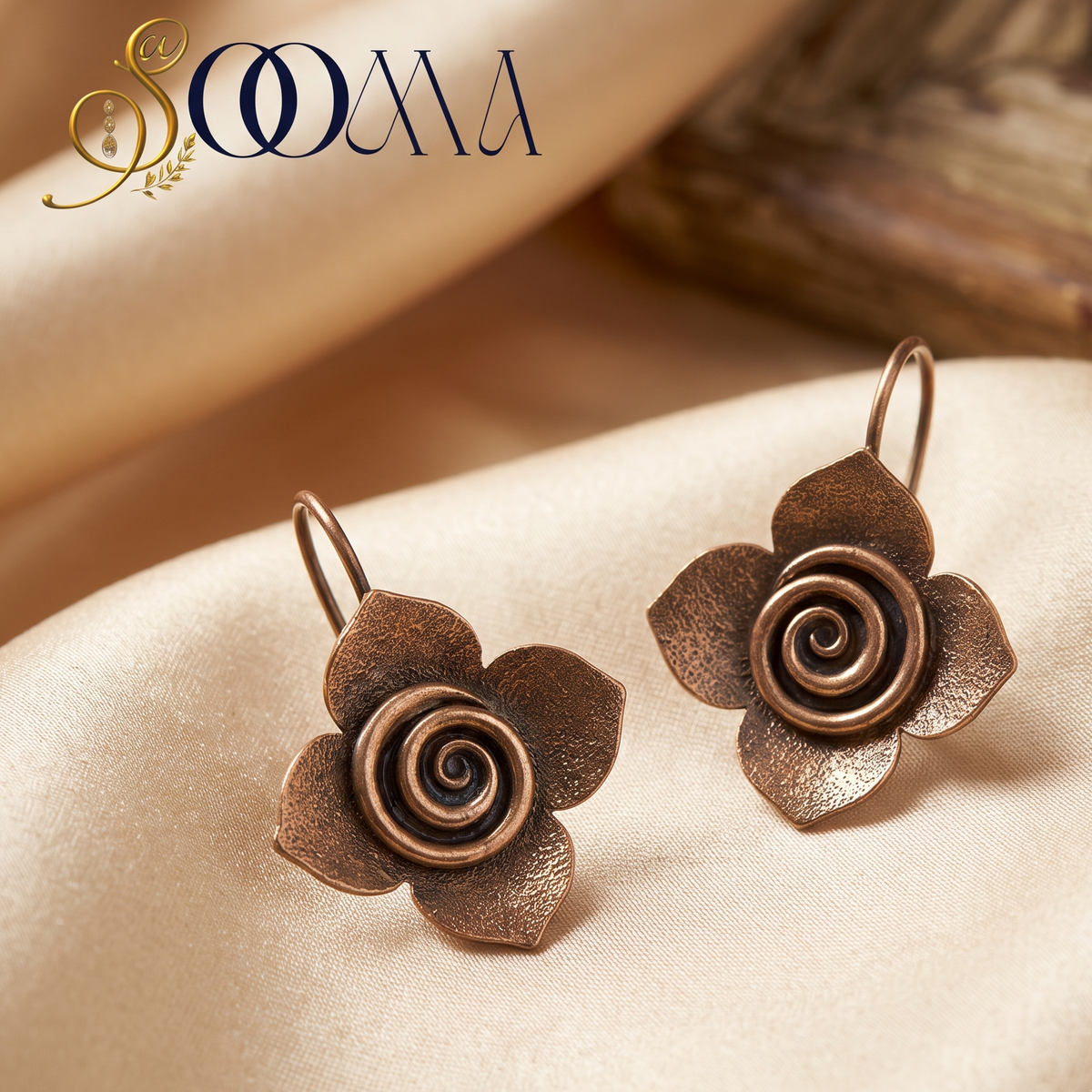 Pair of handcrafted antiqued silver spiral flower bugadi ear cuffs displayed flat on smooth beige satin fabric
