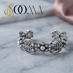 Close up view of an artisan interlocking silver chain bracelet with detailed textured finishes on a warm background