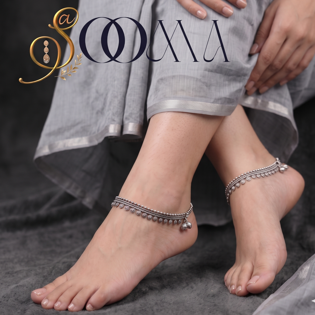 Model wearing handcrafted oxidized silver multi-strand floral charm payal anklets while seated in a grey ethnic outfit