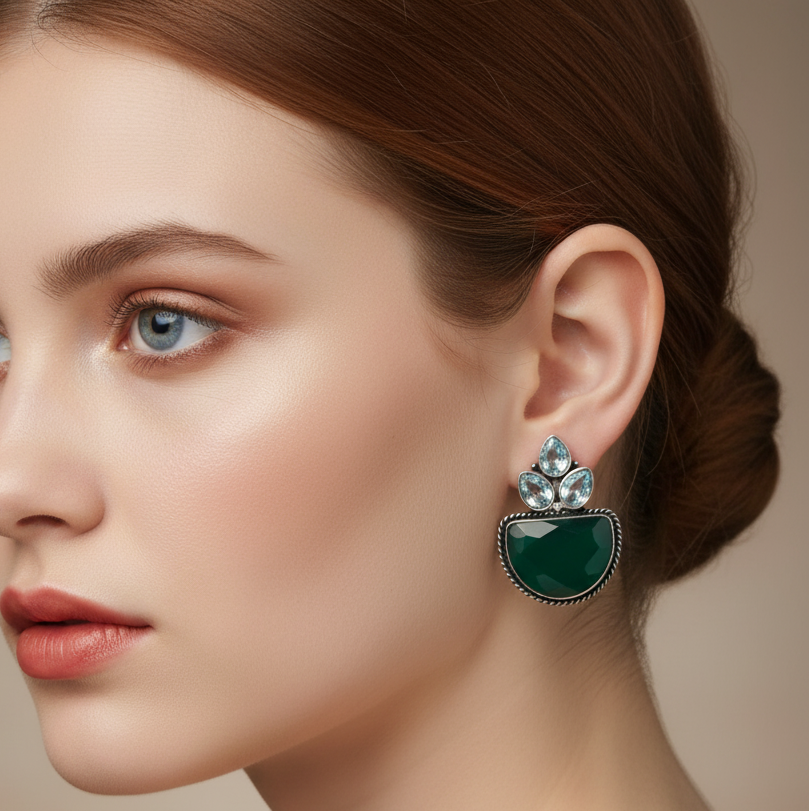 A model wearing a green and silver studearring 
