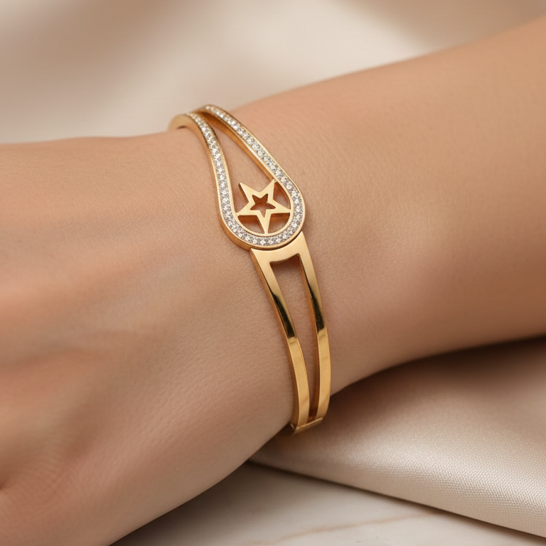 Gold bracelet with star design on a wrist against a beige fabric background