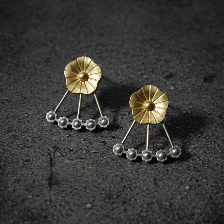 Pair of gold and silver earrings on a dark surface
