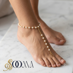 Minimalist gold foot chain jewelry featuring small round pearls close up