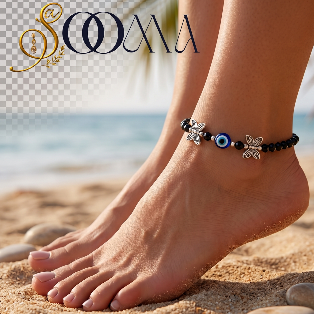 A close-up of a person's feet and ankles standing on a sandy beach, wearing a beaded ankle bracelet with black beads, a blue evil eye charm, and silver-tone floral and star details. The background shows the ocean and palm leaves, and the SOOMA brand logo appears in the top left corner.