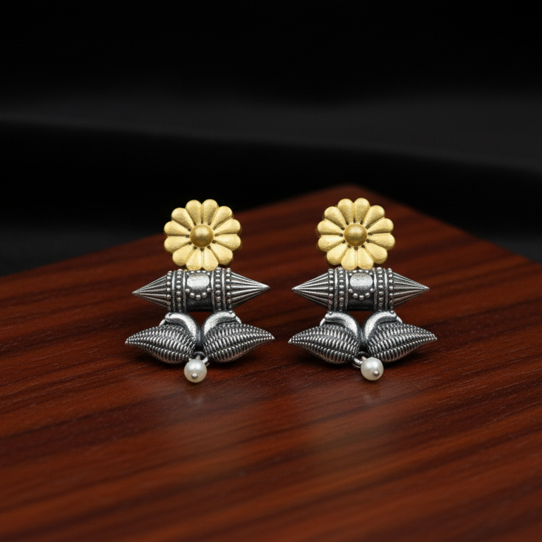 Pair of silver and gold floral design earrings on a wooden surface