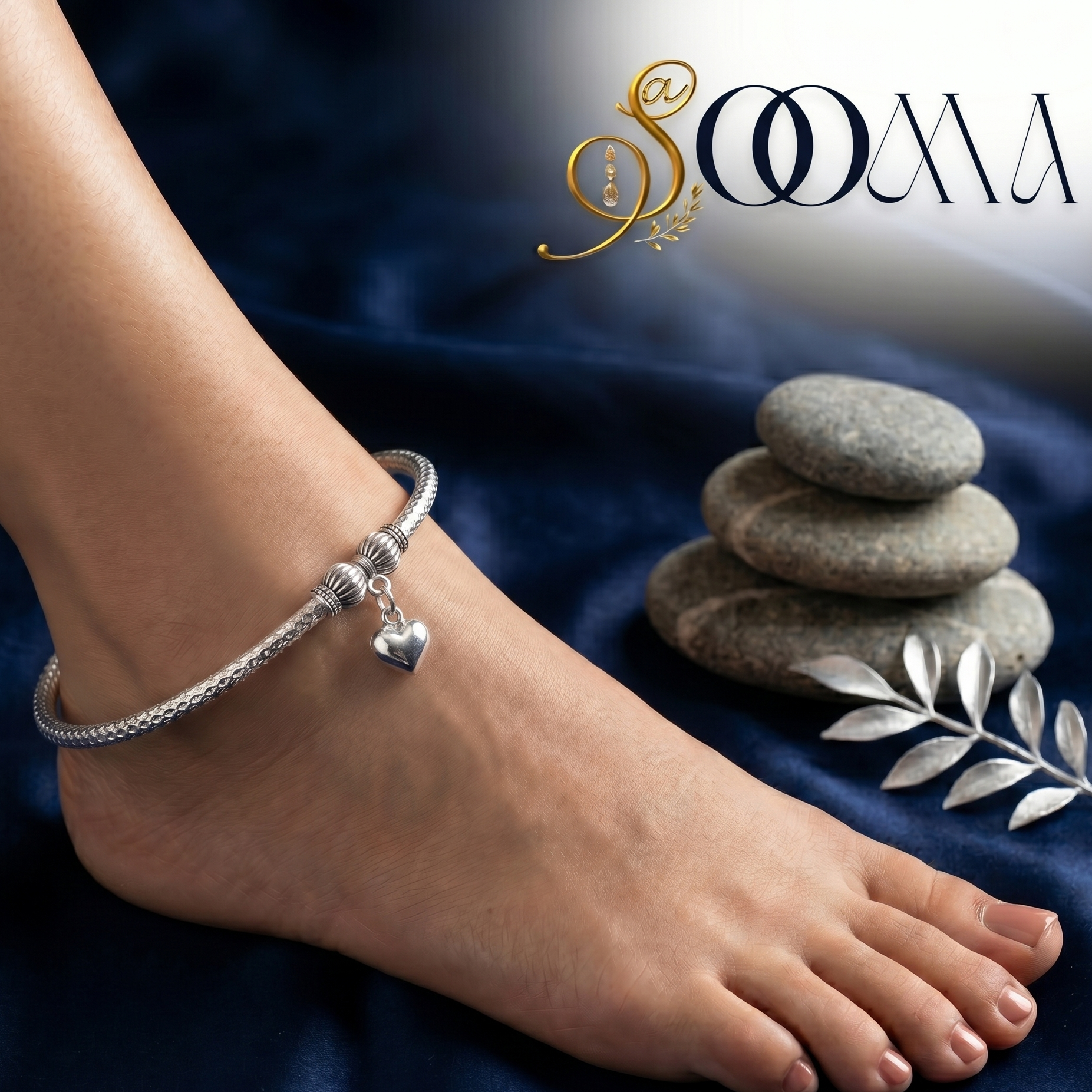 Silver anklet on a foot with stacked stones and 'Sooma' branding.